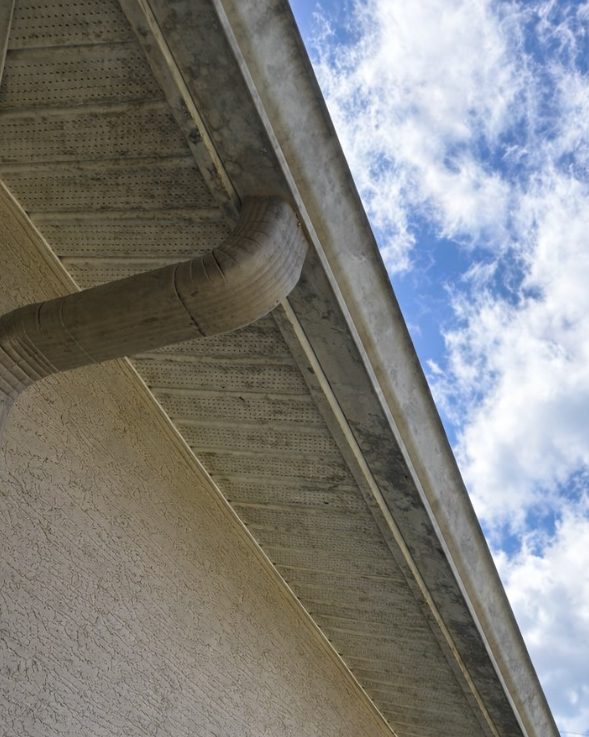 A gutter, downspout and soffit stained grey-black